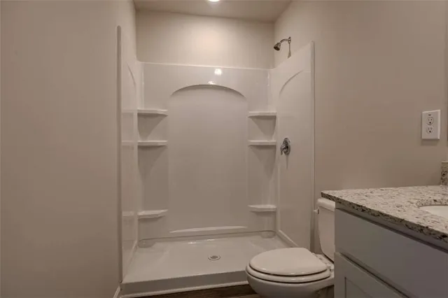 a bathroom with a granite countertop bathtub shower sink vanity and toilet