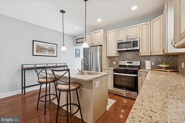 a kitchen with stainless steel appliances granite countertop a stove a refrigerator a oven a sink with a dining table and chairs