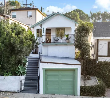 a view of a house with a yard plants and large tree