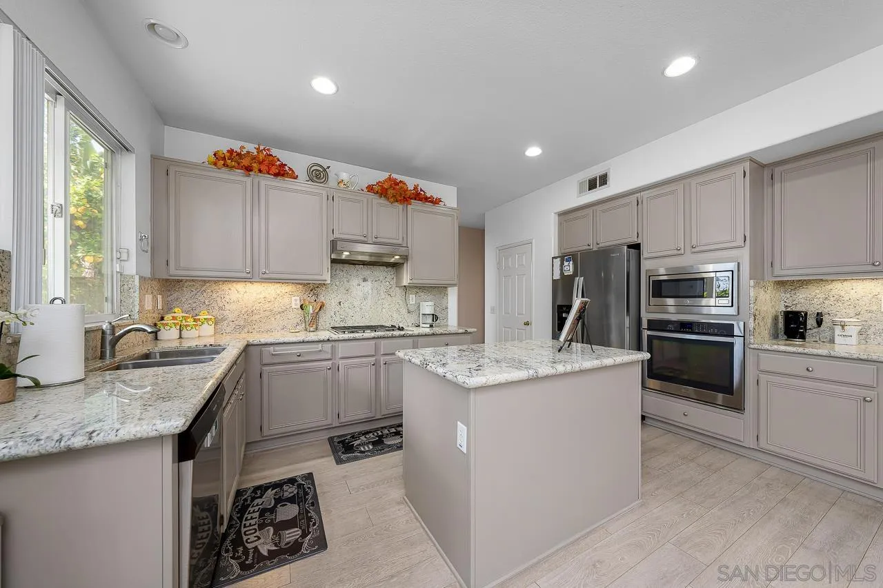 1559 Pleasanton Road Chula Vista, CA 91913 - Photo 7 of 41 a kitchen with kitchen island granite countertop a sink stove refrigerator and cabinets