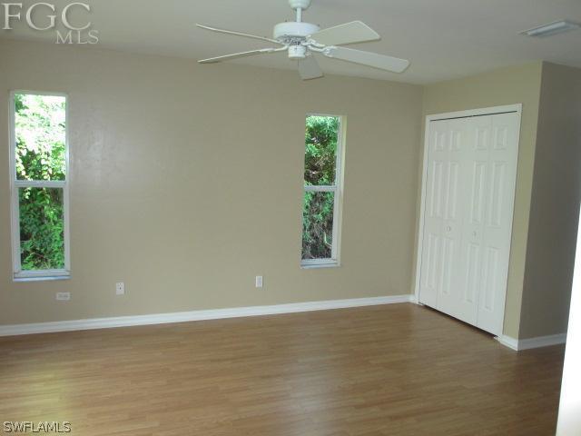 17421 Lee Road Fort Myers, FL 33967 - Photo 7 of 13 an empty room with wooden floor chandelier fan and windows