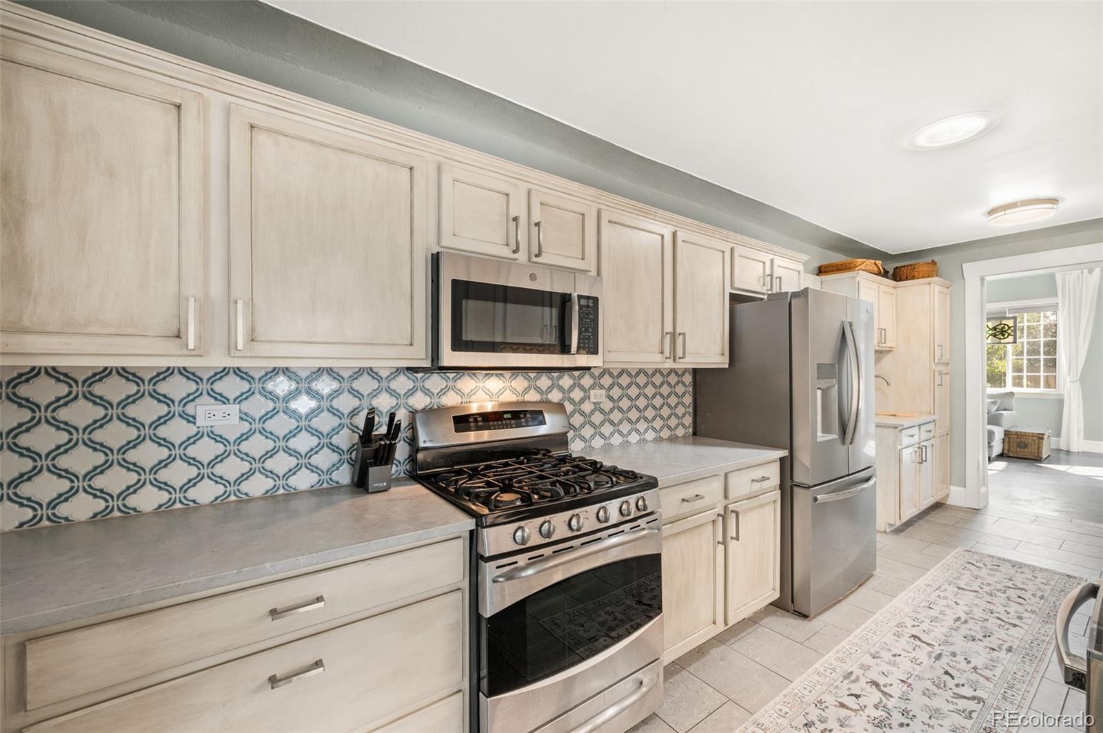 4730 Otis Street Wheat Ridge, CO 80033 - Photo 14 of 34 a kitchen with stainless steel appliances white cabinets and a stove top oven