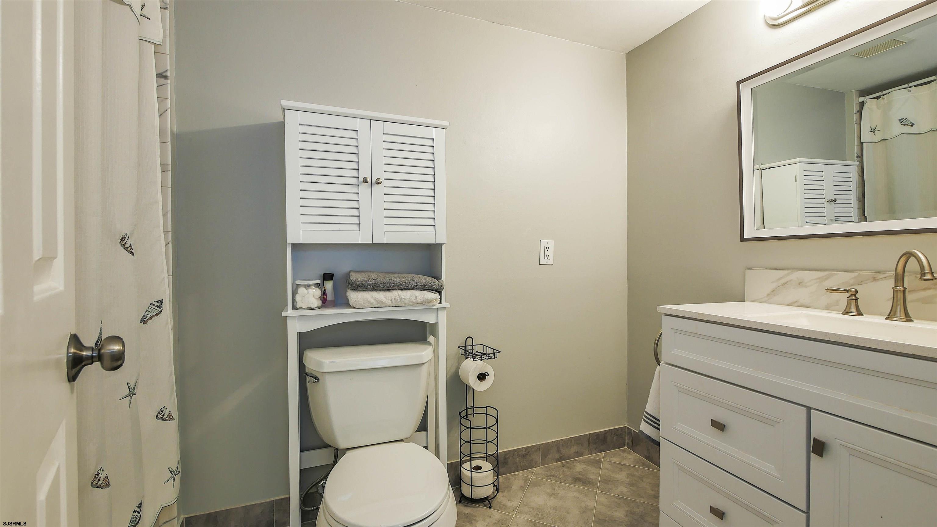 4318 West Brigantine Avenue, Unit D1 Brigantine, NJ 08203 - Photo 19 of 30 a bathroom with a granite countertop toilet sink and mirror