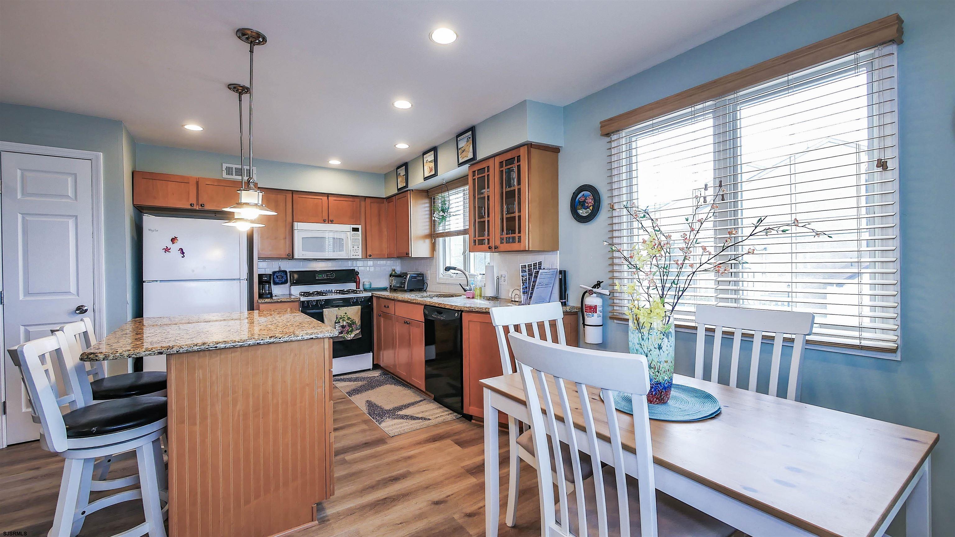 4318 West Brigantine Avenue, Unit D1 Brigantine, NJ 08203 - Photo 6 of 30 a kitchen with stainless steel appliances kitchen island granite countertop a table chairs and a refrigerator
