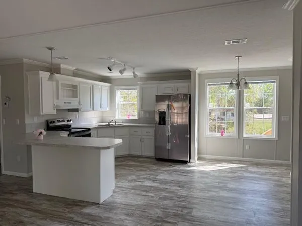 a kitchen with stainless steel appliances a stove top oven a sink a refrigerator and white cabinets with wooden floor