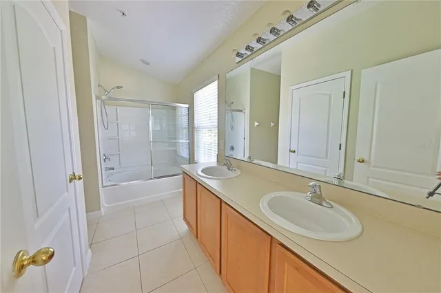 a bathroom with a sink double vanity granite tub shower and mirror