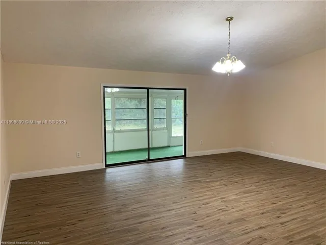 a view of empty room with wooden floor and window