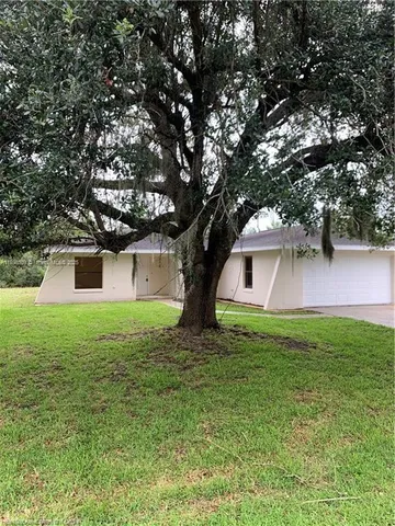 a view of a yard in front of a house with large trees