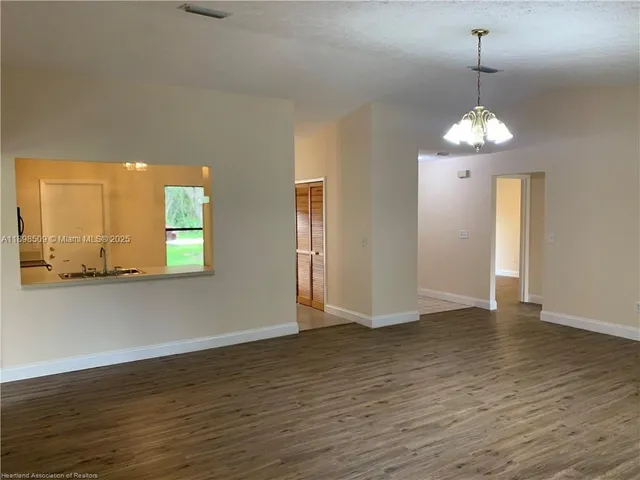 a view of a room with wooden floor chandelier and windows