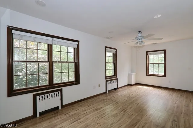 an empty room with wooden floor and ceiling fan