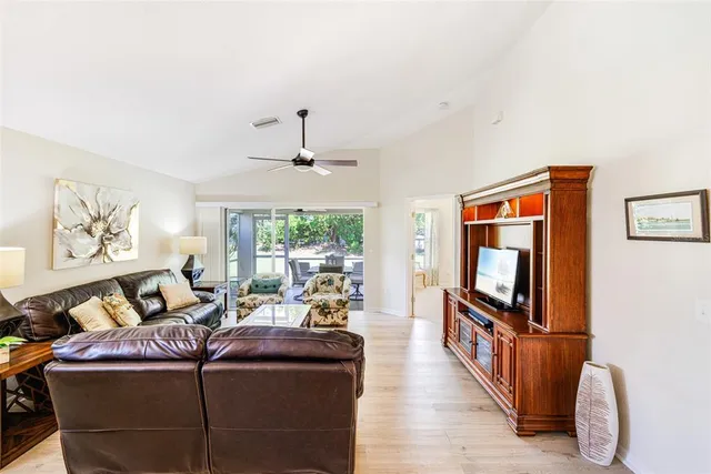 a living room with furniture a flat screen tv and a floor to ceiling window