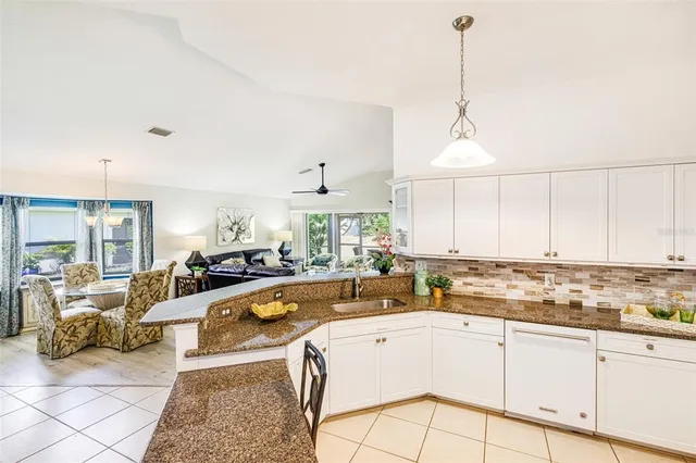 a view of a kitchen with kitchen island a large window cabinets a sink and stainless steel appliances