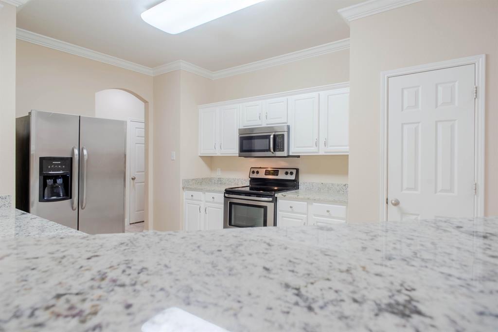 4929 Spur Ridge Court Fort Worth, TX 76244 - Photo 13 of 34 a kitchen with granite countertop a stove a sink and a refrigerator