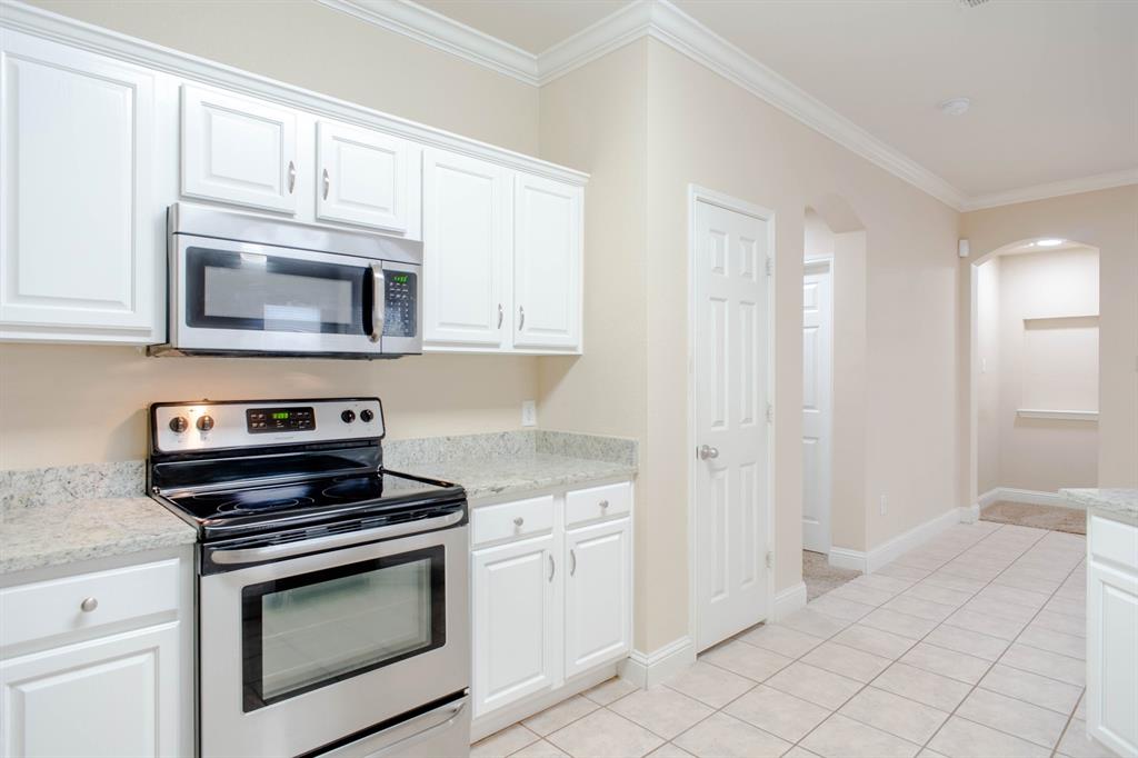 4929 Spur Ridge Court Fort Worth, TX 76244 - Photo 17 of 34 a kitchen with white cabinets and appliances