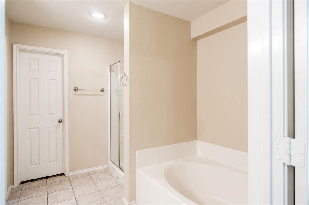 4929 Spur Ridge Court Fort Worth, TX 76244 - Photo 23 of 34 a white bath tub sitting in a en suite bathroom