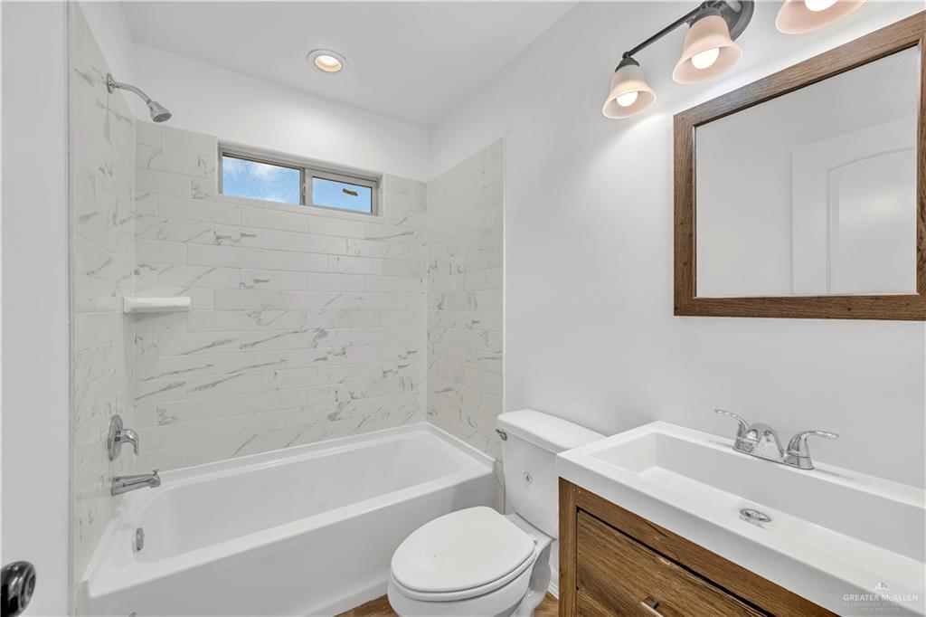 304 Santa Fe Street Alton, TX 78573 - Photo 17 of 31 a bathroom with a toilet a sink a mirror a bathtub and vanity