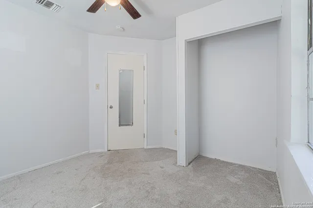 an empty room with chandelier fan