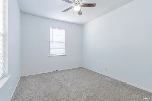 an empty room with a window and a fan