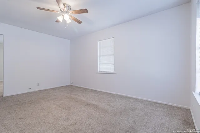 an empty room with a window and ceiling fan