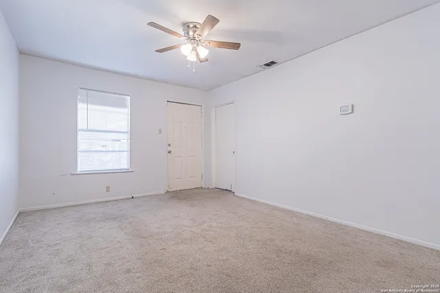 an empty room with a window and a ceiling fan
