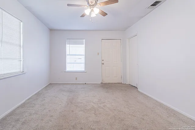 an empty room with windows and chandelier fan