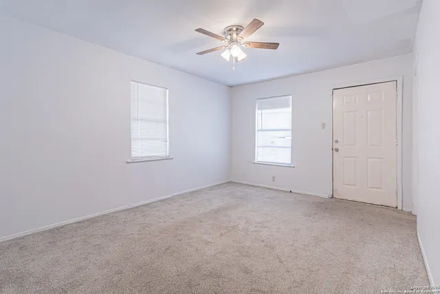 an empty room with windows and ceiling fan
