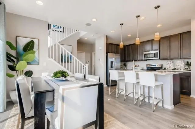 a kitchen with stainless steel appliances kitchen island granite countertop a refrigerator a stove top oven and a sink with wooden floor