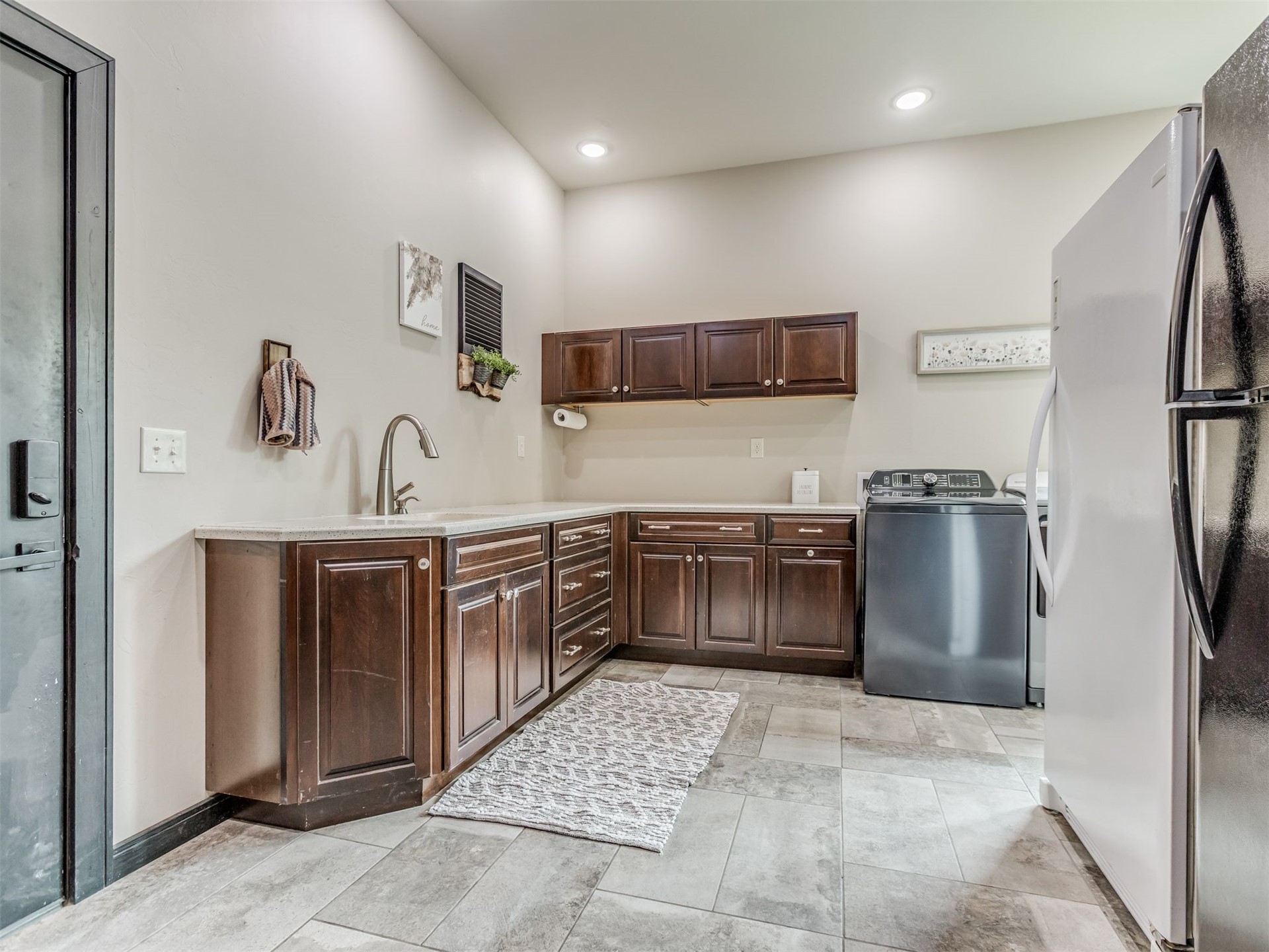 1073 Hidden Ridge Road Stigler, OK 74462 - Photo 36 of 56 Laundry room featuring wood-finish cabinetry, light-toned countertops, and a stainless steel sink with a gooseneck faucet