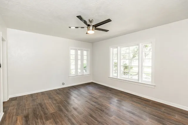 a view of an empty room with wooden floor and a window