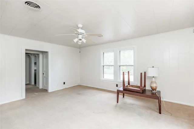 an empty room with windows and ceiling fan