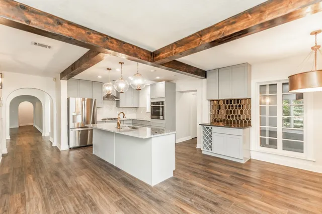 a large kitchen with stainless steel appliances kitchen island a large counter space and wooden floor