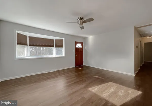 a view of an empty room with a window and wooden floor