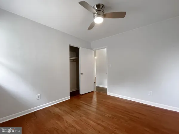 an empty room with wooden floor and ceiling fan