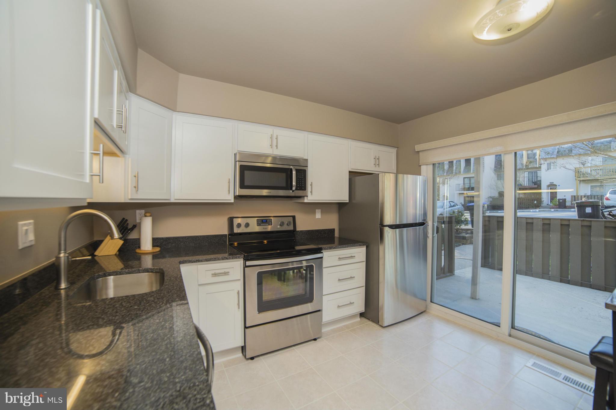 1613 Valencia Way Reston, VA 20190 - Photo 11 of 29 a kitchen with stainless steel appliances granite countertop a stove top oven a sink and a refrigerator
