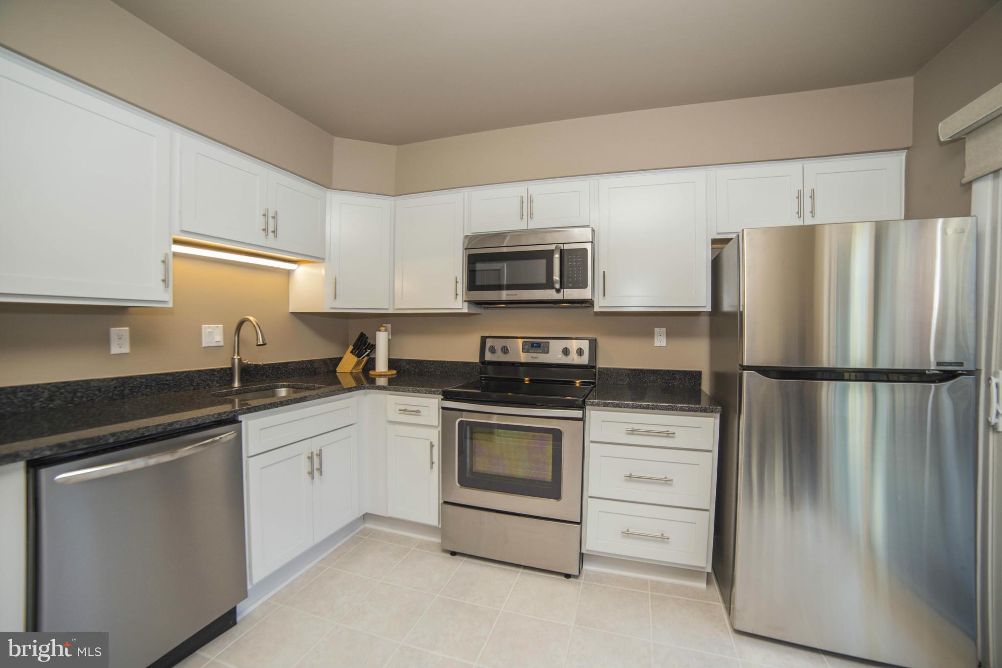 1613 Valencia Way Reston, VA 20190 - Photo 10 of 29 a kitchen with white cabinets and stainless steel appliances