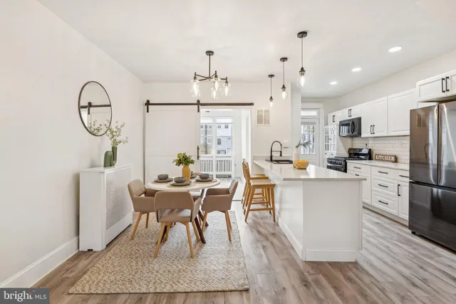 a dining room with stainless steel appliances kitchen island granite countertop a table chairs refrigerator and microwave