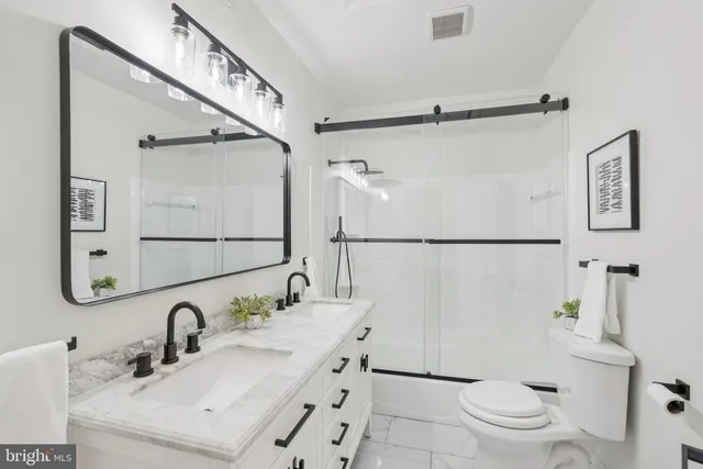 a bathroom with a granite countertop sink mirror vanity and toilet