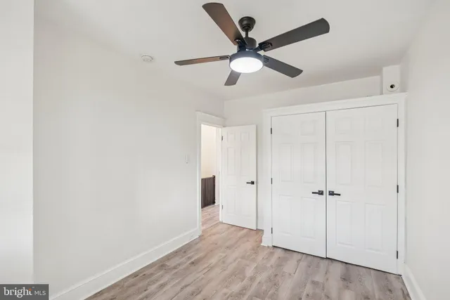 an empty room with wooden floor closet and ceiling fan