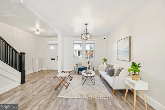 a living room with furniture a chandelier and wooden floor