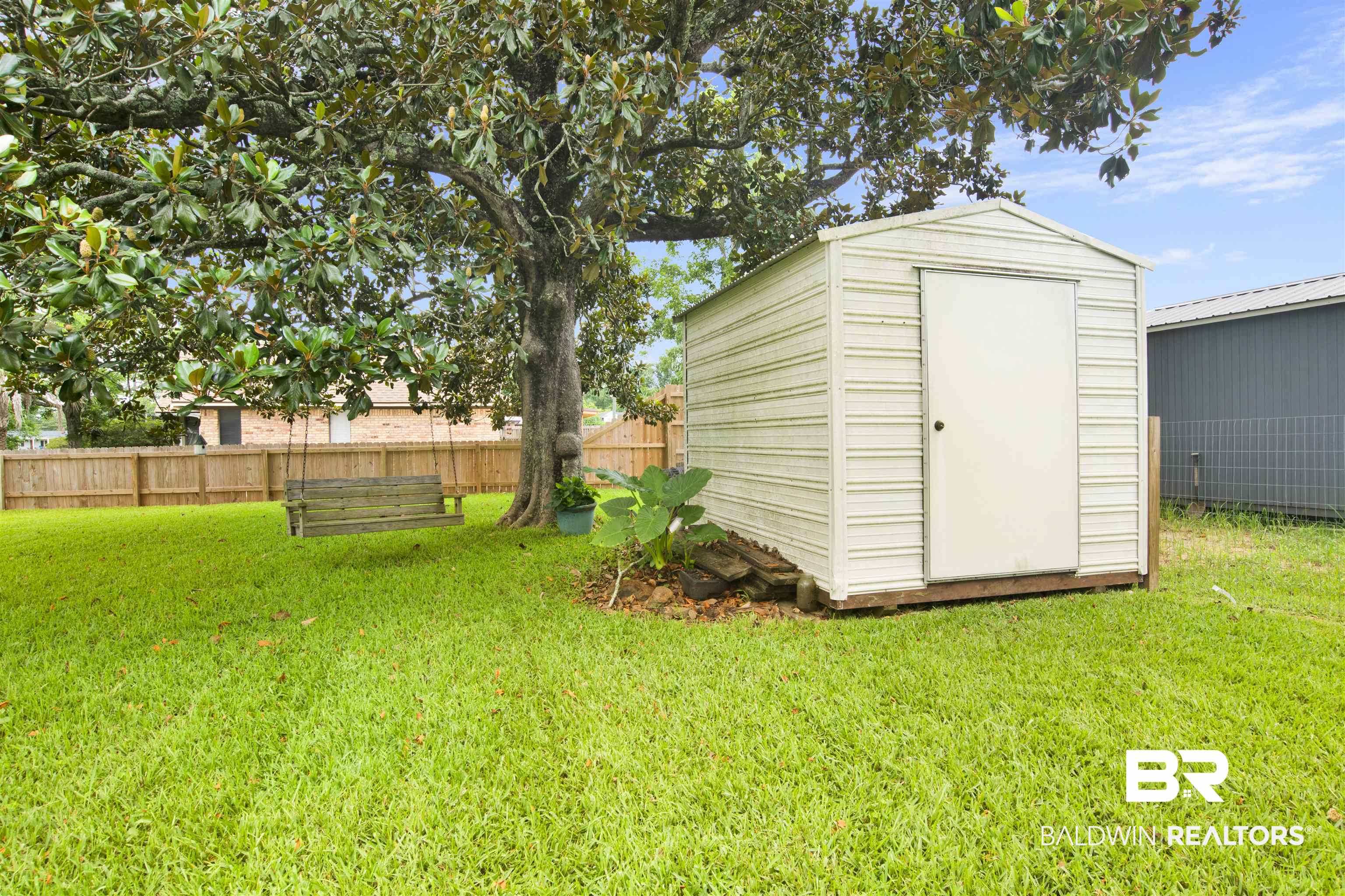 1100 North Pine Street Foley, AL 36535 - Photo 27 of 30 Expansive backyard featuring a lush lawn, mature shade tree, and a metal storage shed