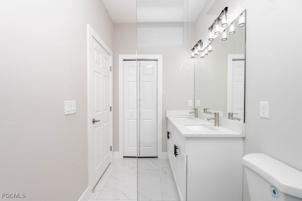4417 22nd Street Southwest Lehigh Acres, FL 33973 - Photo 15 of 36 a bathroom with a sink vanity mirror and toilet