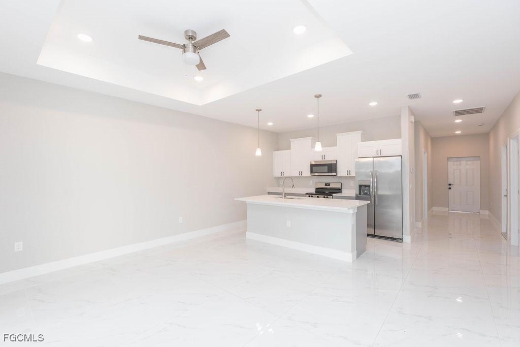 4417 22nd Street Southwest Lehigh Acres, FL 33973 - Photo 32 of 36 a large white kitchen with a refrigerator a stove top oven a sink and cabinets