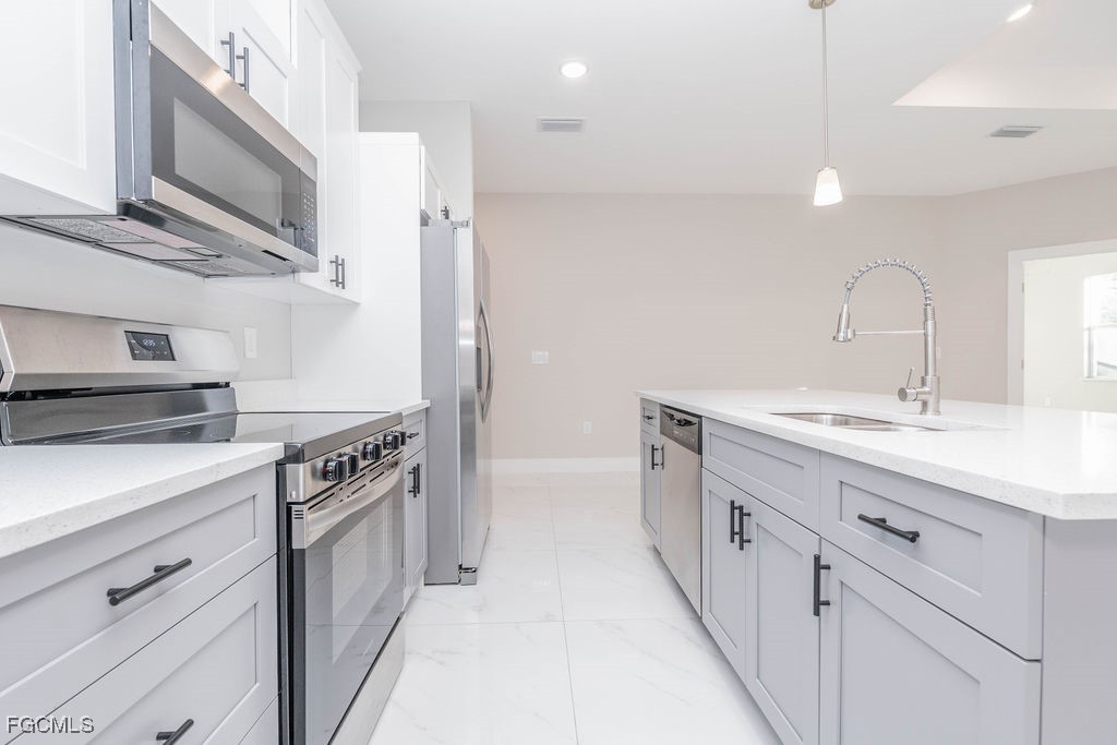 4417 22nd Street Southwest Lehigh Acres, FL 33973 - Photo 33 of 36 a kitchen with stainless steel appliances a sink dishwasher stove and white cabinets