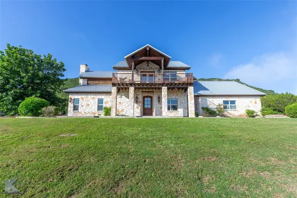 a view of a big house with a big yard and large trees