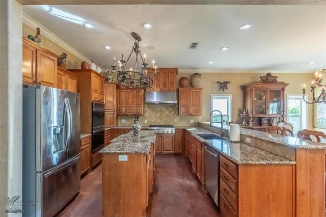 a kitchen with stainless steel appliances granite countertop a refrigerator a sink dishwasher a stove and a dining table with wooden floor