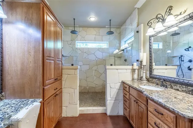 a bathroom with a granite countertop sink a mirror and shower