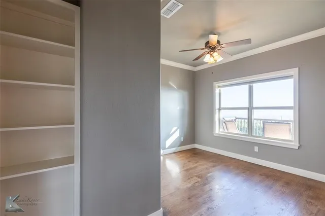 a view of an empty room with a window and a ceiling fan