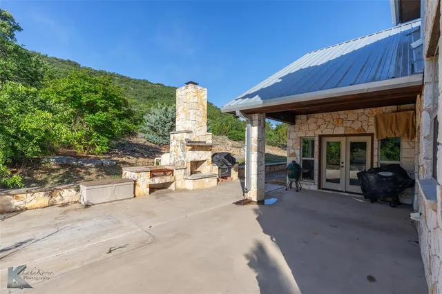 a view of a patio with table and chairs under an umbrella with a large tree
