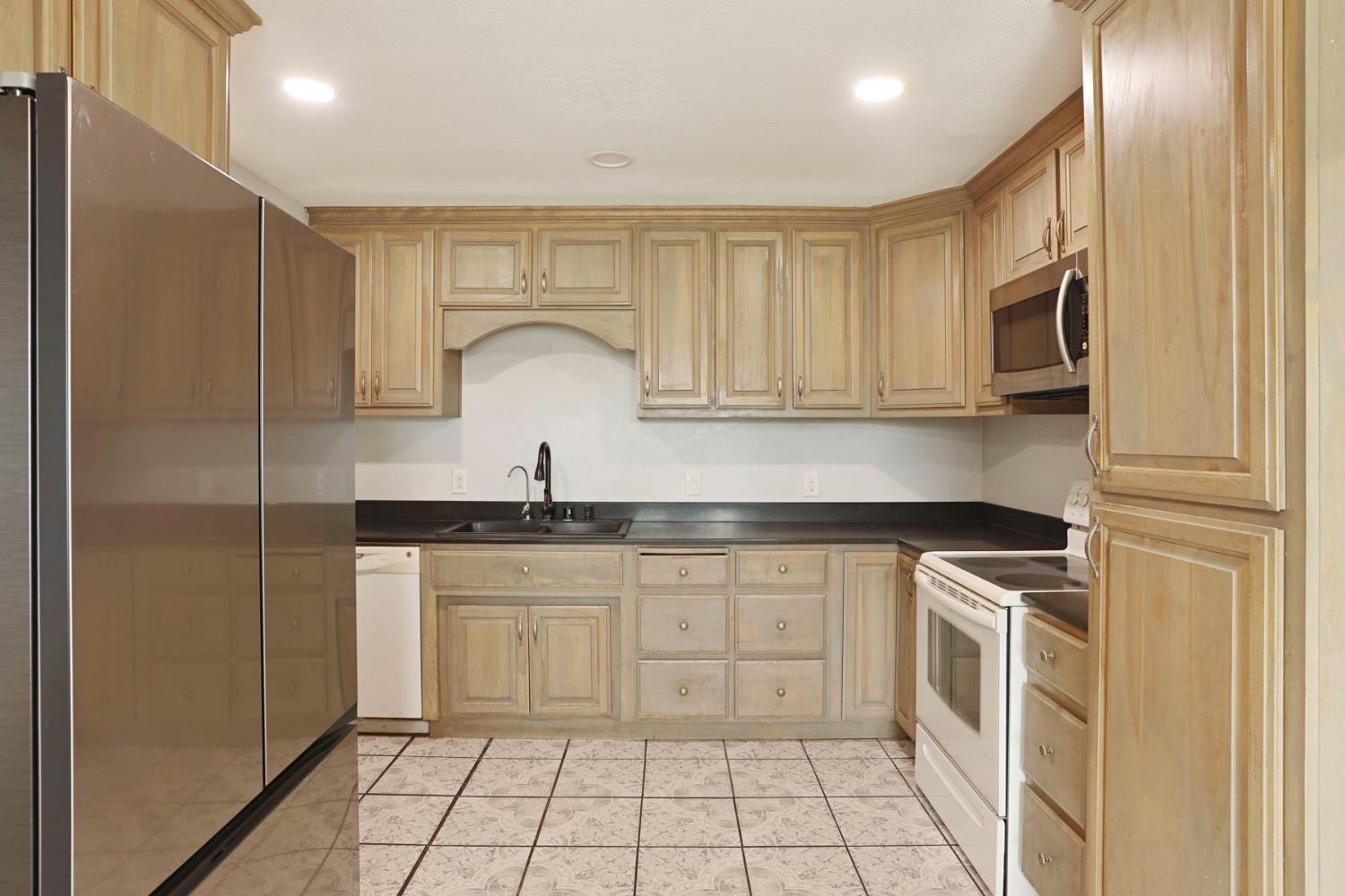 2443 Fern Street Merced, CA 95348 - Photo 11 of 50 a kitchen with stainless steel appliances granite countertop a stove a sink and a refrigerator