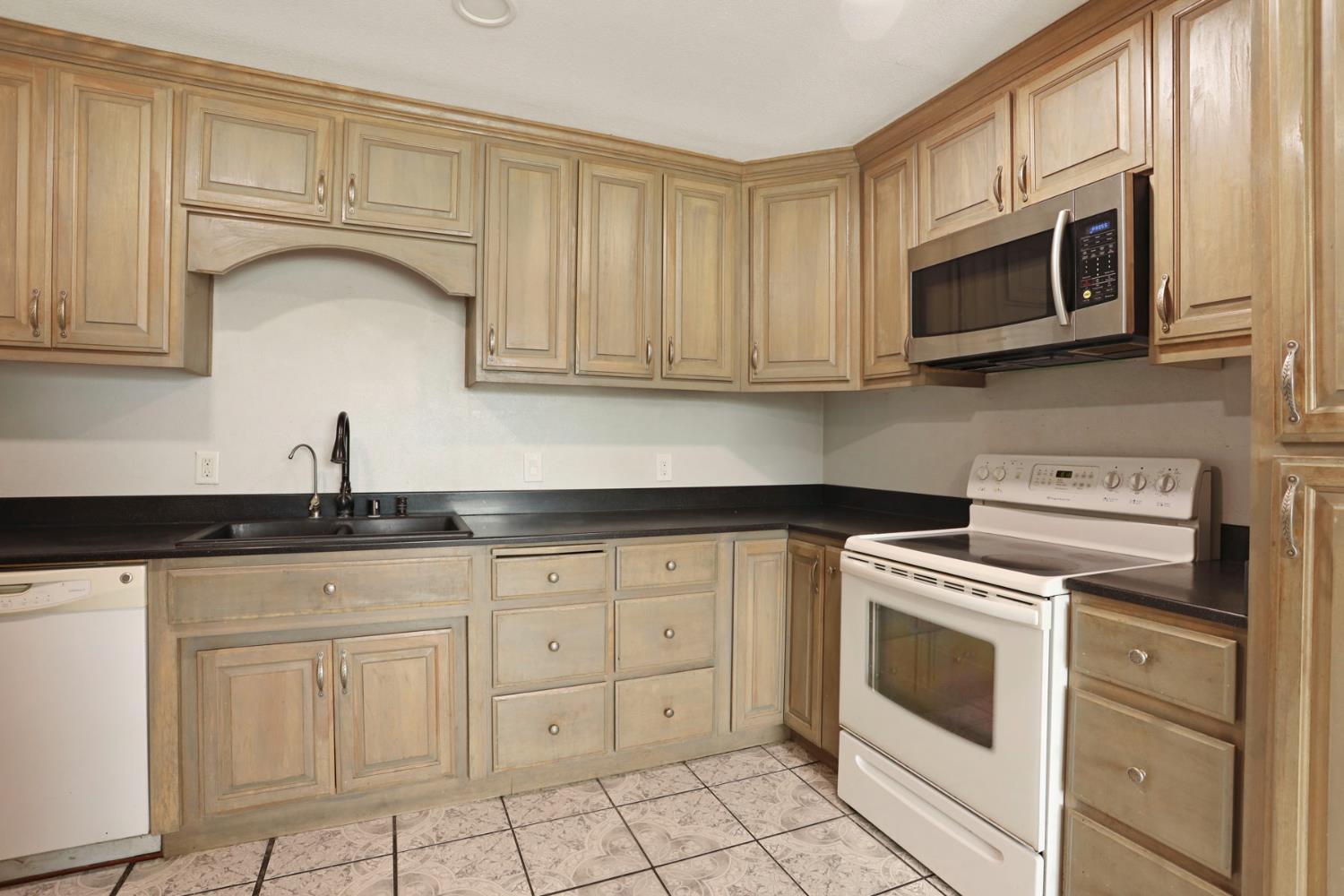 2443 Fern Street Merced, CA 95348 - Photo 12 of 50 a kitchen with white cabinets and stainless steel appliances